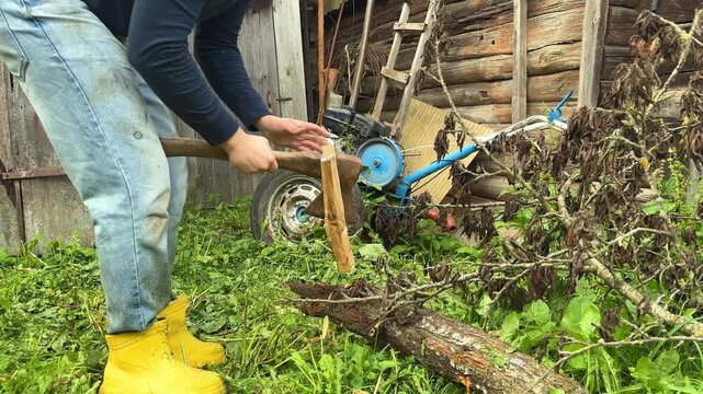 Person chopping and splitting a fallen log with an axe in a rustic yard, manual firewood preparation for the cold season