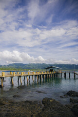 Fototapeta premium Rustic concrete pier over calm water with mountains