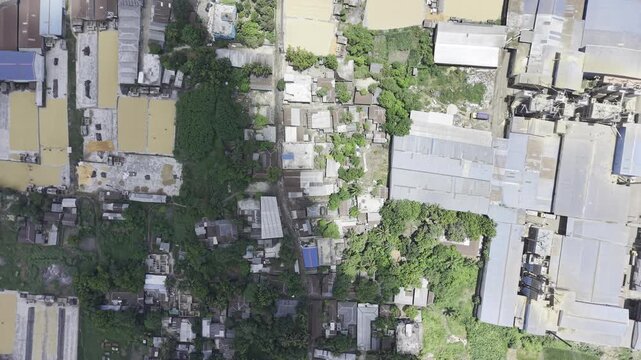Top down aerial view of a slum beside industrial buildings