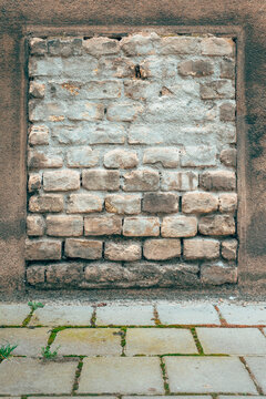 Old brickwork filling a former window opening on a stucco wall. Concept of urban decay, architectural history, blocked passages, and building renovation.