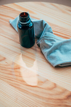 Bottle of natural wood finishing flax oil with a soft cotton cloth on a light wooden surface. Wood protection, furniture finishing and DIY woodworking concept.