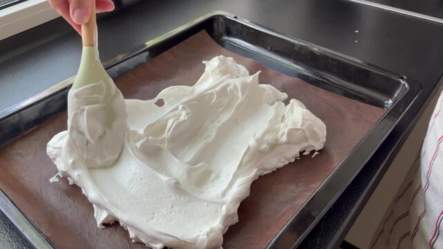 Homemade baking. The baking process of making desserts like pavlova, meringue cookies, or a swiss roll base in a home kitchen.