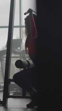 Focused woman performing seated cable lat pulldown exercise in modern gym environment, highlighting strength training, posture control, and athletic physique development