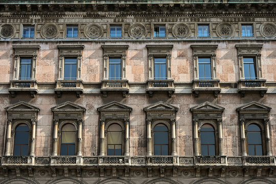 Ornate historic facade with arched windows and balconies in Milan, Italy