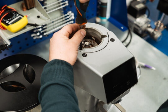 Service worker disassembles professional coffee grinder for maintenance and repair