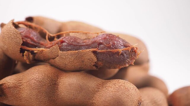 Fresh sweet tamarind pods macro shot showcasing organic fruit texture and brown shell husk.