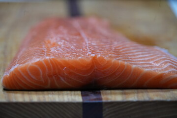 A filet of raw atlantic salmon on a wooden cutting board. © scott