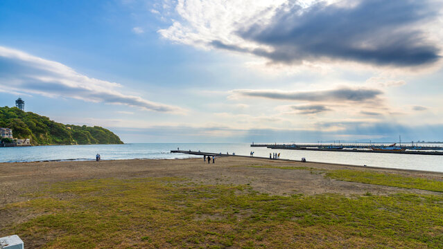 Coastal beach view of Enoshima island under cloudy sky in Japan