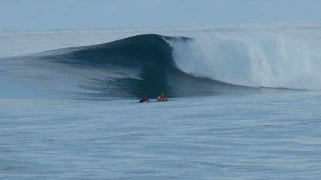 Surfer paddles towards the line up on the uncrowded surfing spot of the Sultans in the Maldives with the big and perfect glassy waves