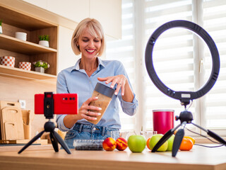 Food blogger recording a step-by-step smoothie tutorial with a compact smartphone tripod, ring light, and fresh ingredients.