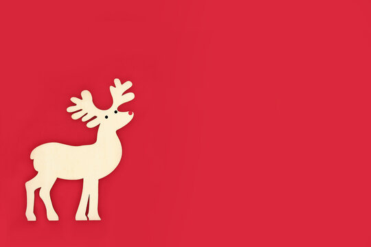 Wooden red nose reindeer Christmas tree decoration on red background. Eco friendly vintage ornament for festive holiday season. 