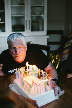Senior man blows out lots of birthday candles
