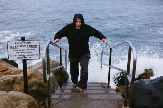 Man escapes crashing wave on beach stairs