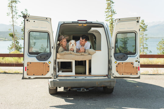 Couple embracing vanlife with puppy in scenic mountain camper setting
