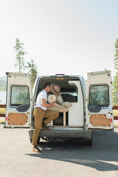 Couple kissing beside camper van with puppy at scenic lake