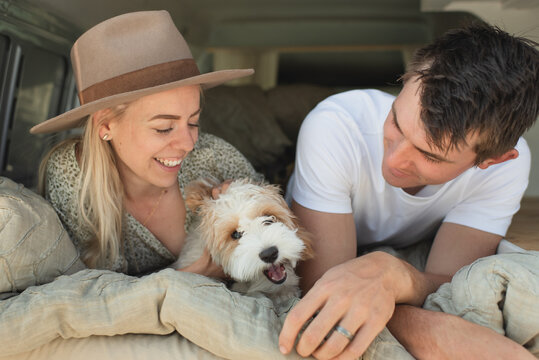 Smiling couple and their puppy relaxing in a van on vacation