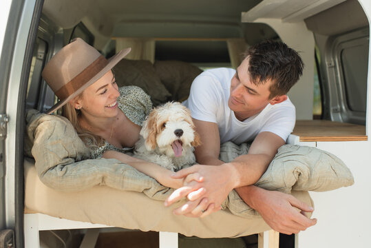 Happy couple with pet dog lying in camper van on a road trip