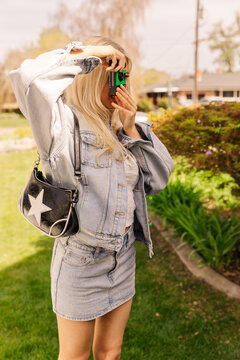 Fashionable blonde woman taking a picture outside