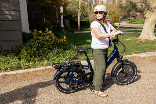 Woman pauses with her electric bike on a sunny day