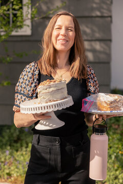 Smiling woman holding a cake stand and baked goods