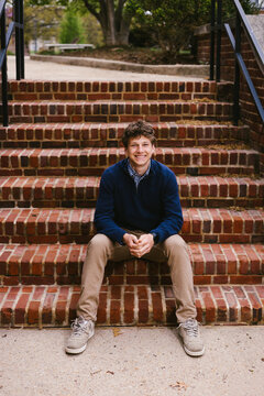 Smiling young man sitting on outdoor brick steps