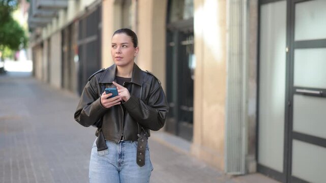 Joyful woman with a phone in hands walks around city, she looks at maps in a mobile application . High quality 4k footage
