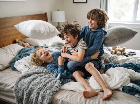 Three cheerful brothers playing, wrestling, and laughing on bed in the bedroom in the morning.