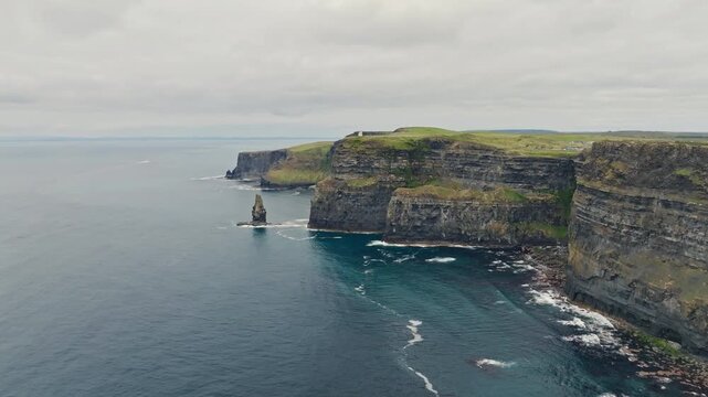 Layered sea cliffs and Atlantic coastline at the Cliffs of Moher in County Clare, Ireland, form an aerial sightseeing view with a rock stack and white surf.