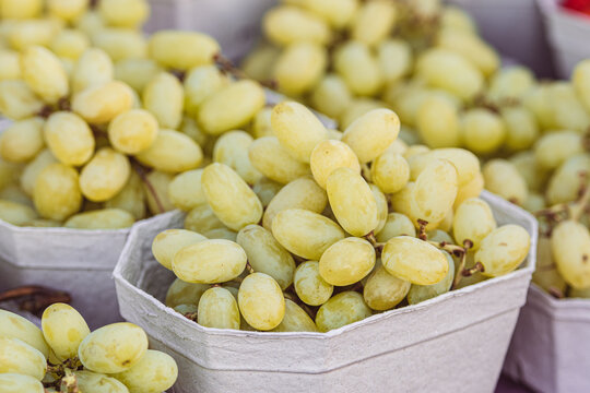 White table grapes displayed in cardboard or paper baskets for sale in a fruit and vegetables market