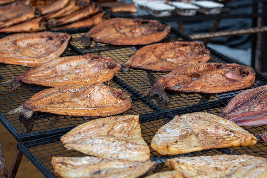 Close-up of smoked fish fillets displayed on a rack in a farmer street market, ready to eat