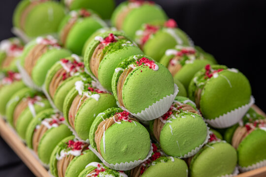 Close-up of green pistachio macarons filled with cream and decorated with dried berries and nuts. Elegant French dessert with vibrant colors, perfect for pastry, confectionery and gourmet food