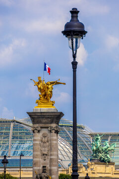 Golden gilded statue against glass roof of grand palais in paris