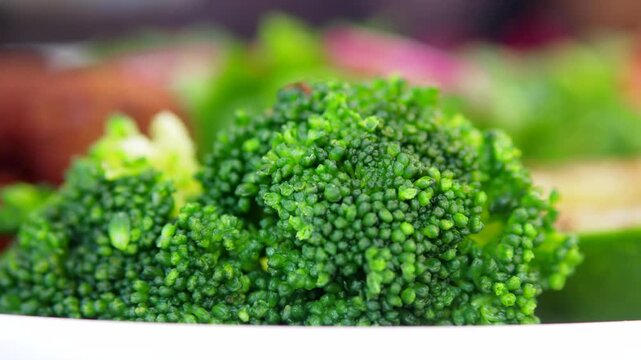 Fresh broccoli floret rotating slowly on a plate, showcasing its vibrant green color and texture.