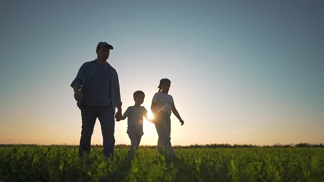Family walking field sunset view. Father firmly holding hands daughter son together. Silhouette father daughter son joyful field. Walking holding hands family close. Sunset shines on family together.