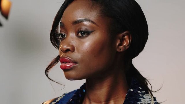 Studio light appearing, model turning head into 3 or 4 profile posing for portrait with sequin colla