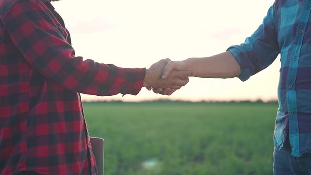 Close handshake connects farmer trust with man partnership. Field handshake emphasizes teamwork. Green crop field shows handshake power. Partnership handshake fosters business trust under sunset.