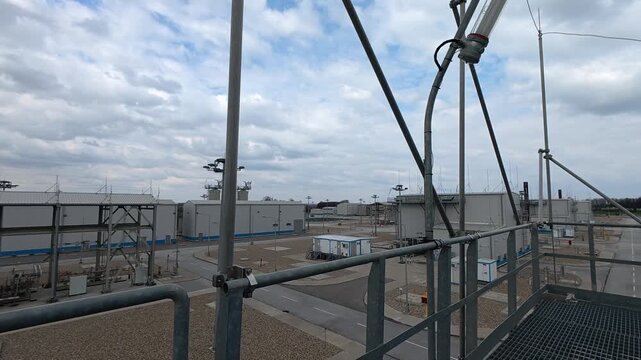 A breathtaking first-person or wide-angle video of a person standing on the upper tier of an industrial facility, gazing out over the entire site spread below like a map. 