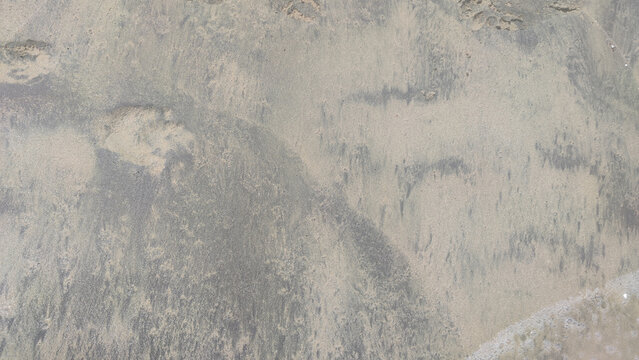 Close-up view of sand contaminated with black petroleum oil spill residue. Environmental pollution texture of crude oil and dark tar on sandy ground.   