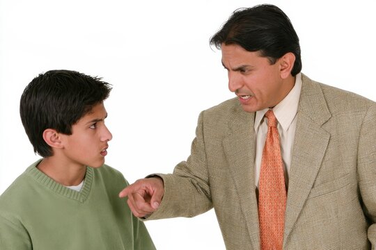 Stern adult man pointing while confronting teenage boy in green sweater, isolated against white background, expressive disagreement and tense interpersonal exchange portrait