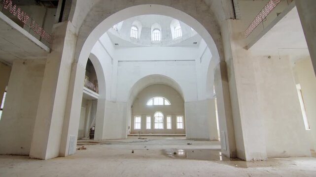 Abandoned crumbling mansion with tall arched windows. Grand and magnificent building filling with elegant arches and sweeping curves