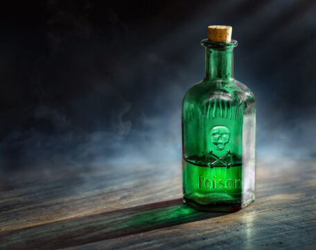 Glass poison bottle with skull and bones. Danger sign, symbol of death. Concept background on poison poisoning, pharmaceutical, chemistry, medical topic. Poison, venom, toxin, toxic background.