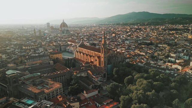 Cinematic drone panorama frames Basilica Santa Croce in the foreground with Palazzo Vecchio, the Duomo and Tuscan hills beyond.