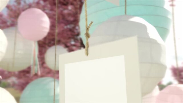 Blank hanging picture frame mock up with pastel paper lanterns in soft garden setting.