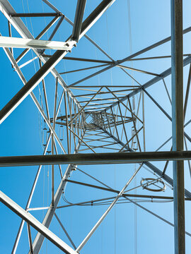 View from inside a metal power transmission tower against a clear blue sky