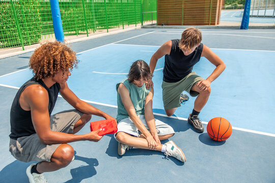 Friends helping injured basketball player on court