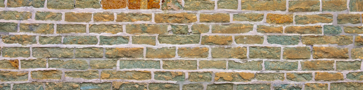 Old weathered brick wall texture background with yellow and green bricks
