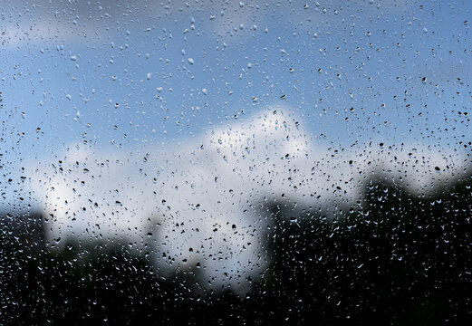 Raindrops streak a window, blurring the view