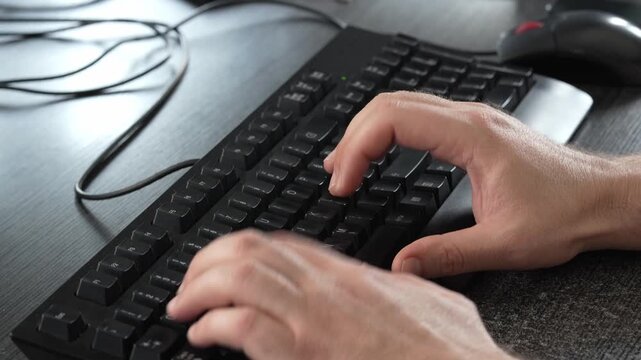 Close-up of hands typing on a computer keyboard at a desk, showing everyday office work, digital communication, data entry and computer use.