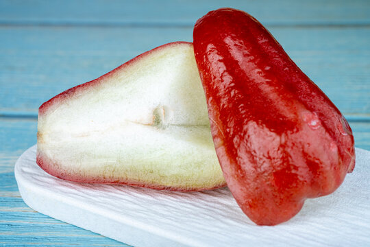 Crisp and juicy red wax apple slice presented in studio lighting with soft shadows.