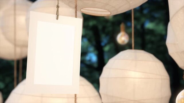 Blank white paper card hanging among glowing decorative paper lanterns.